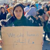 A refugee woman holds sign while protesting with other women in Mytilini center, asking for better conditions in Moria and the right to move on from the island.