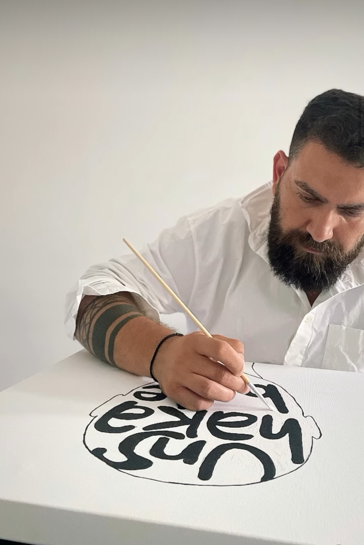 Greek artist Giorgos in his studio, surrounded by minimalist paintings inspired by Greek heritage, history, and modern social themes.
