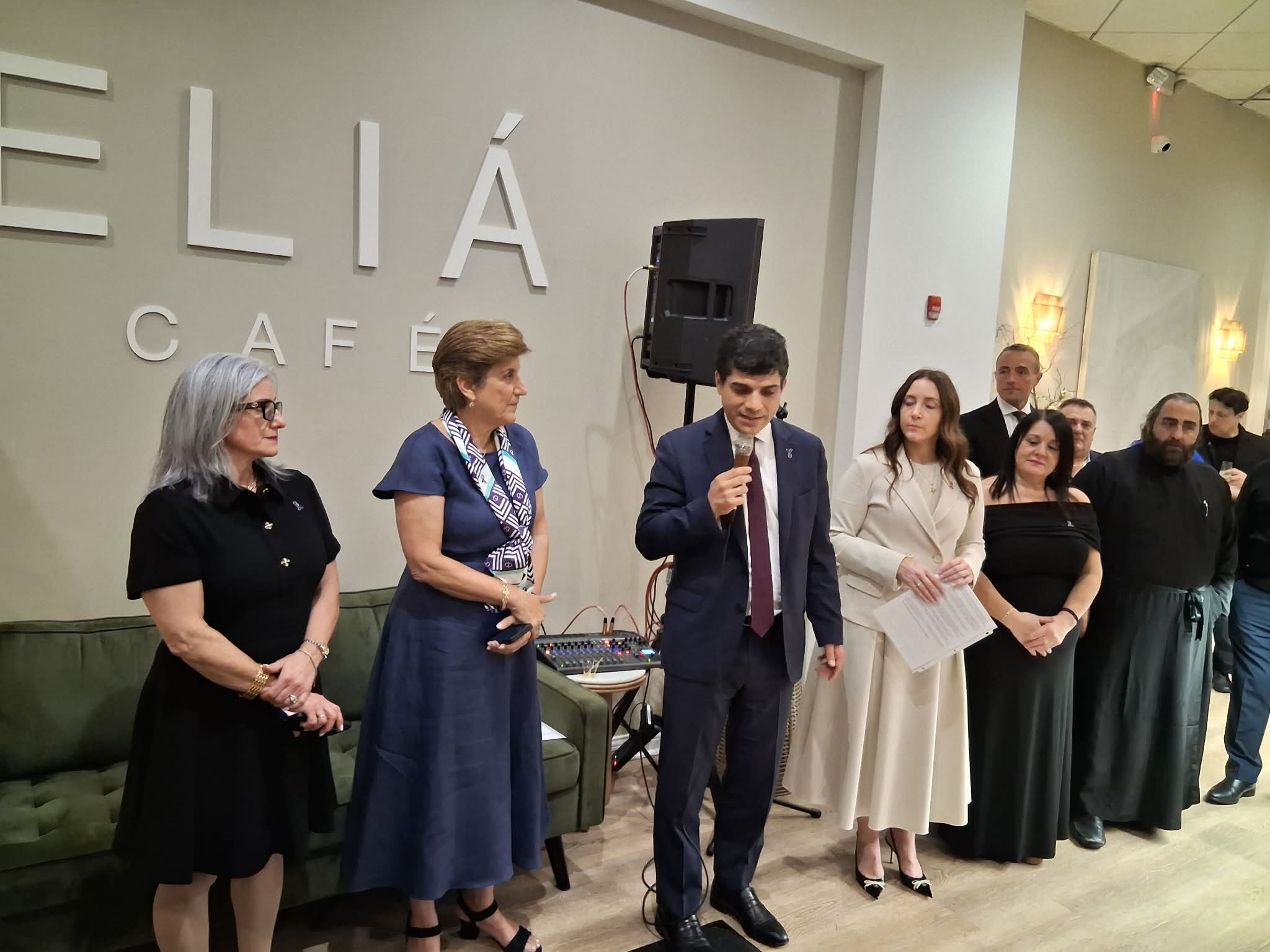 Consulate General for Greece Emmanuel Koumbarakis at the mic. In the white dress is Bianca Pigounakis, event chair, and in blue dress) is Diane Kounalakis, chair of the PanCretan Association of America